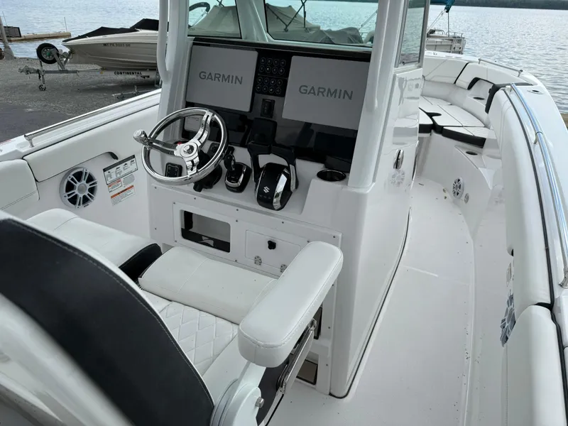 Slide: The Image of 2025 Stingray 273 CC boat cockpit with Garmin navigation systems and sleek white seating. - 11
