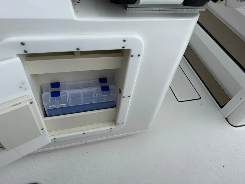 Slide: The Image of 2025 Stingray 273 CC boat storage compartment with tackle box inside. - 12