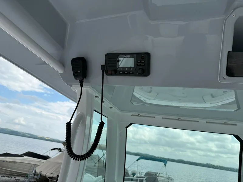 Slide: The Image of 2025 Stingray 273 CC boat interior with radio equipment, overlooking a serene water view. - 17