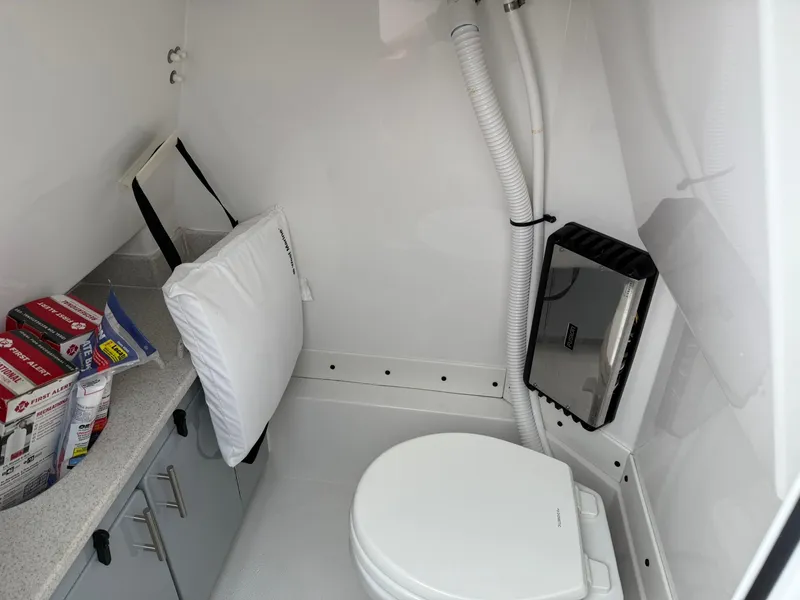 Slide: The Image of 2025 Stingray 273 CC boat interior with compact bathroom, featuring a toilet and storage cabinets. - 25