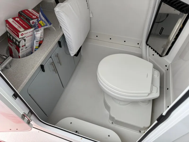 Slide: The Image of 2025 Stingray 273 CC boat interior bathroom with toilet and storage cabinets. - 26