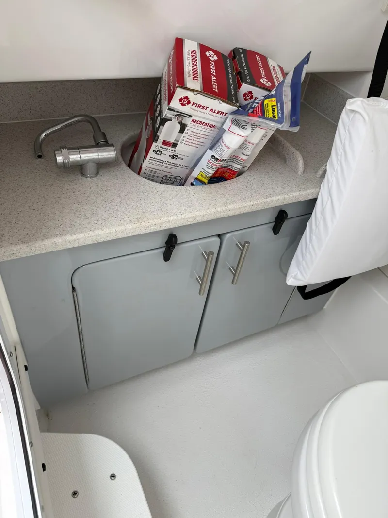 Slide: The Image of 2025 Stingray 273 CC boat interior with sink, cabinets, and fire extinguishers. - 27