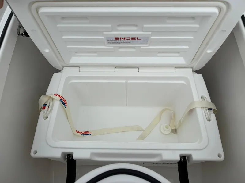 Slide: The Image of Open Engel cooler inside 2025 Stingray 273 CC boat, featuring secure straps and spacious interior. - 33