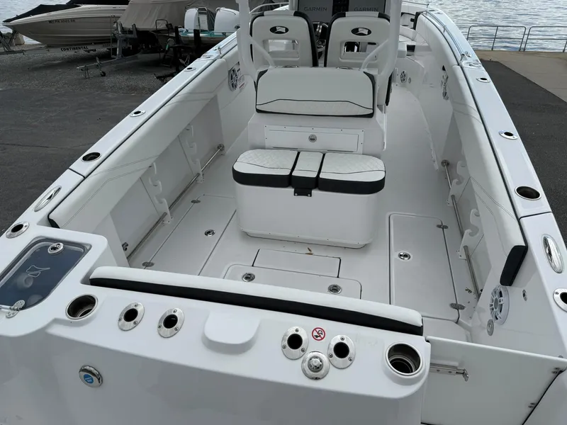 Slide: The Image of 2025 Stingray 273 CC boat interior with seating and storage, docked by the water. - 8