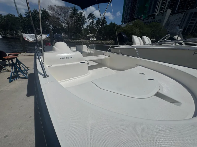 Slide: The Image of 2004 Boston Whaler 150 Sport boat docked, featuring sleek white design and spacious seating. - 10
