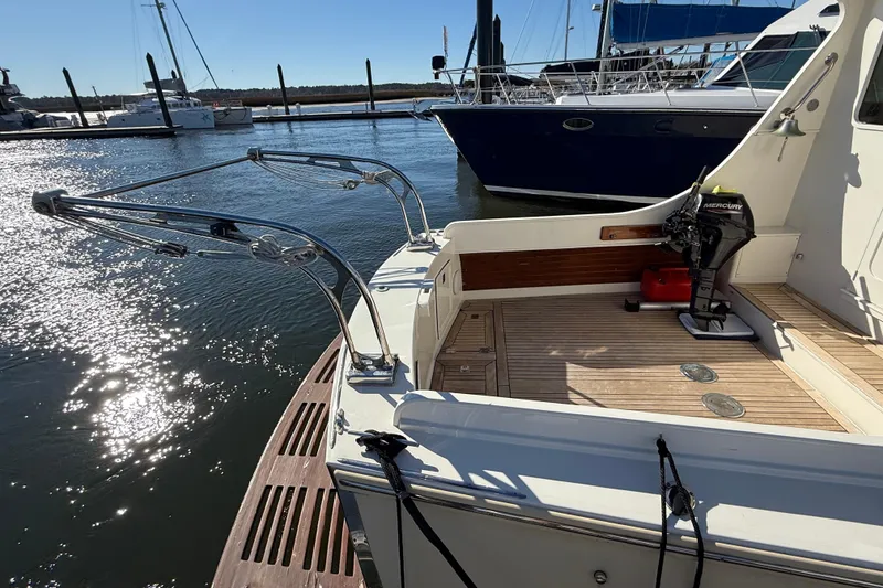 Slide: The Image of 2006 Mast & Mallet Thomas Point 40 boat docked, featuring a wooden deck and Mercury outboard motor. - 16