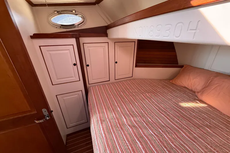 Slide: The Image of Cozy cabin interior of 2006 Mast & Mallet Thomas Point 40 with striped bedding and storage cabinets. - 37