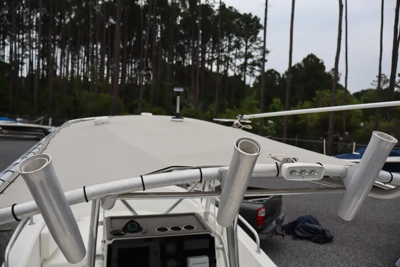 Slide: The Image of 2004 Edgewater 225CC boat with rod holders and canopy, parked near a forested area. - 19