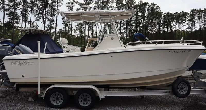 Slide: The Image of 2004 Edgewater 225CC boat on trailer, parked outdoors with trees in background. - 2
