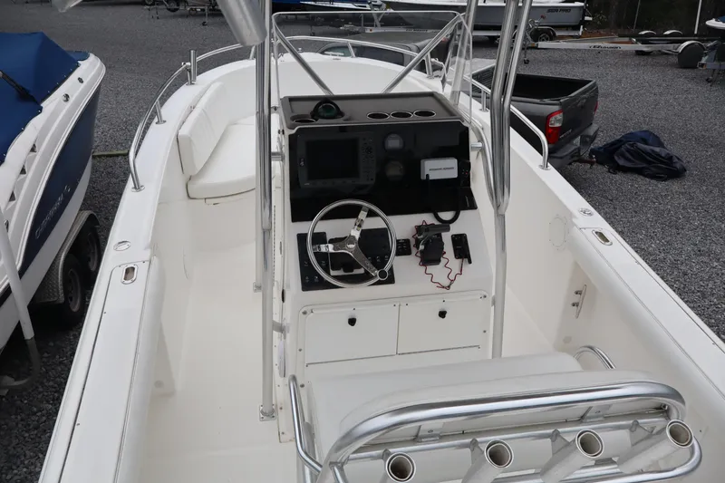 Slide: The Image of 2004 Edgewater 225CC boat interior with steering console and seating, parked on gravel. - 20