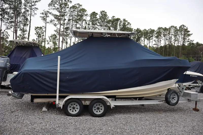 Slide: The Image of 2004 Edgewater 225CC boat covered on trailer, parked on gravel lot. - 5