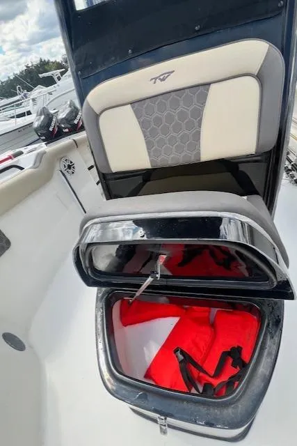 Slide: The Image of 2020 Tidewater 272 CC Adventure boat seat with storage compartment open, revealing red life jackets. - 17