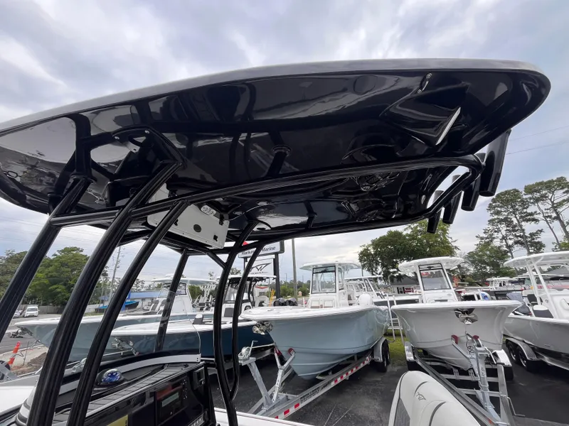 Slide: The Image of 2021 Tidewater 2500 Carolina Bay boat with black T-top, displayed among other boats. - 14