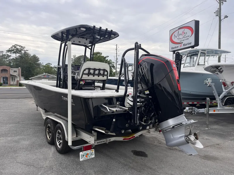 Slide: The Image of 2021 Tidewater 2500 Carolina Bay boat on trailer, parked outdoors near a marine shop. - 2