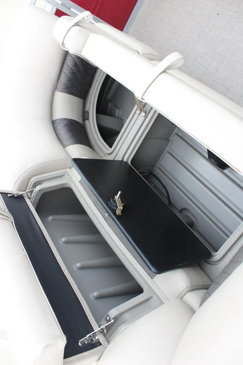 Slide: The Image of 2025 Sun Tracker Party Barge 22 DLX storage compartment with open lid and key. - 18