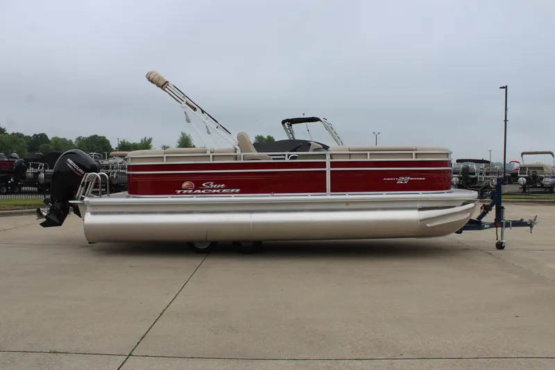 Slide: The Image of 2025 Sun Tracker Party Barge 22 DLX pontoon boat on trailer, parked outdoors. - 4