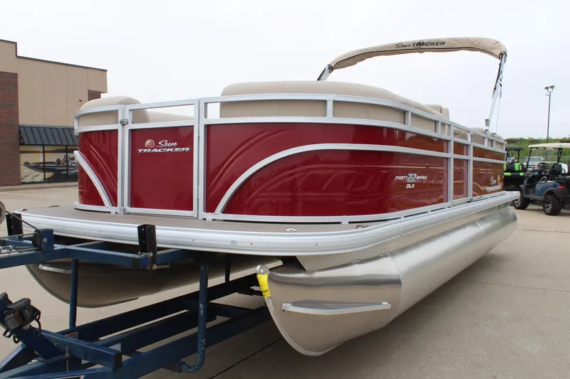 Slide: The Image of 2025 Sun Tracker Party Barge 22 DLX pontoon boat on trailer, red and silver design. - 7
