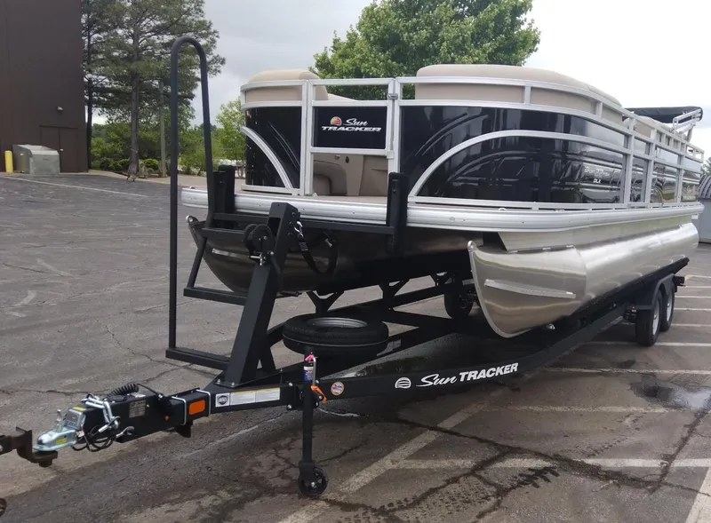 Slide: The Image of 2025 Sun Tracker SportFish 22 DLX pontoon boat on trailer in parking lot. - 2