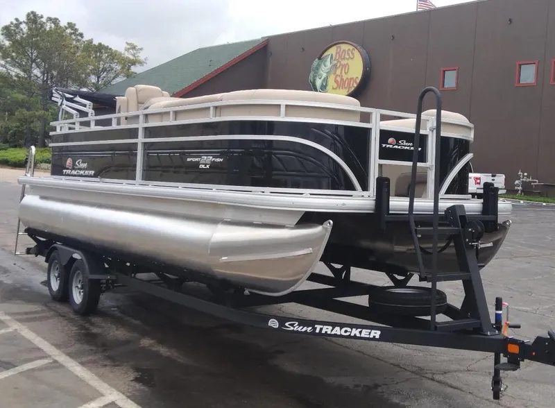 Slide: The Image of 2025 Sun Tracker SportFish 22 DLX pontoon boat on trailer outside store. - 3