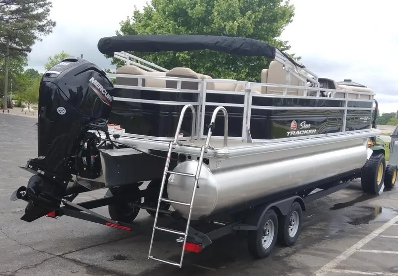 Slide: The Image of 2025 Sun Tracker SportFish 22 DLX pontoon boat on trailer, featuring a Mercury outboard motor. - 4