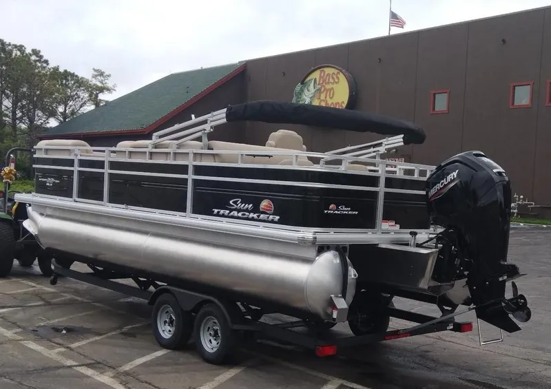 Slide: The Image of 2025 Sun Tracker SportFish 22 DLX pontoon boat on trailer outside Bass Pro Shops. - 5