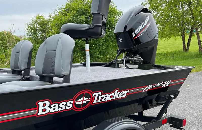 Slide: The Image of 2025 Tracker Bass Tracker Classic XL boat with Mercury engine, parked outdoors. - 2
