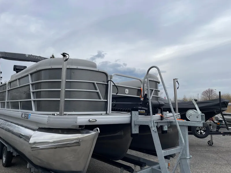 Slide: The Image of 2022 Godfrey Sweetwater 2286 FS pontoon boat on trailer under cloudy sky. - 1