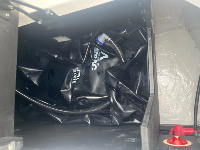 Slide: The Image of 2025 Regal LS4 Surf boat storage compartment with black airbag and hose. - 3
