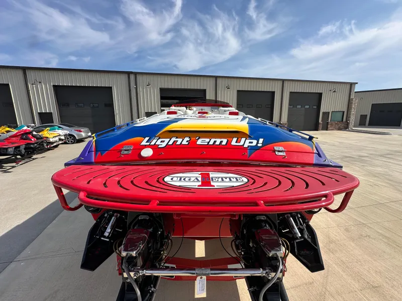 Slide: The Image of 2004 Cigarette 38 Top Gun boat with vibrant design, parked outside a warehouse. - 11