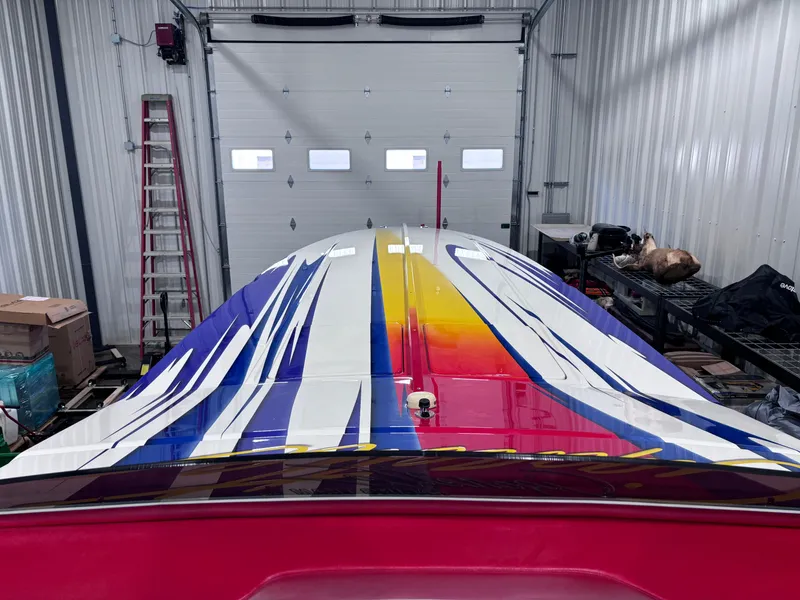 Slide: The Image of 2004 Cigarette 38 Top Gun boat with vibrant, colorful graphics in a garage setting. - 23