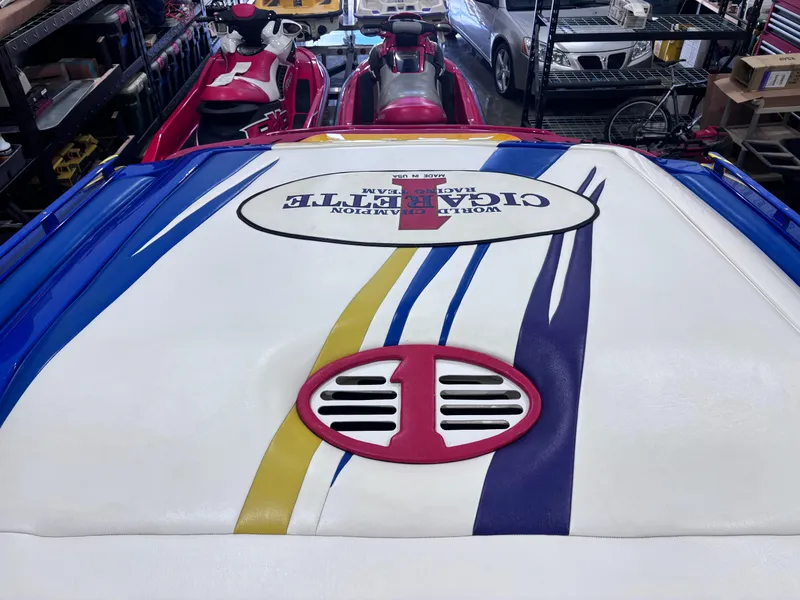 Slide: The Image of 2004 Cigarette 38 Top Gun boat with colorful graphics in a garage setting. - 24