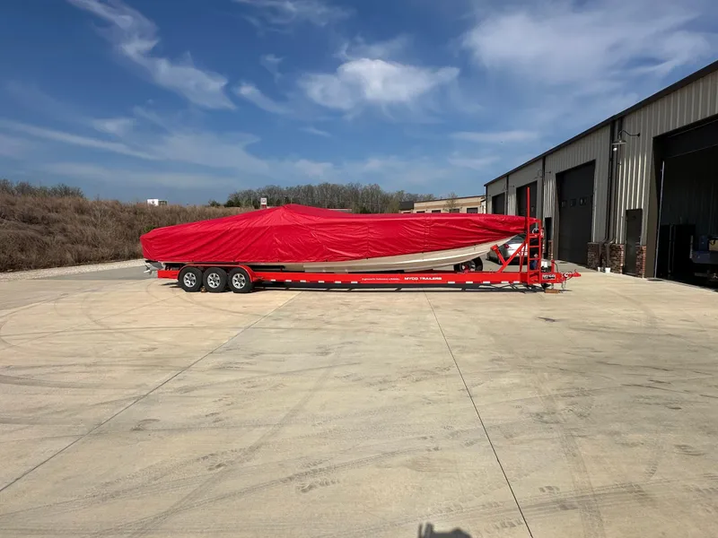 Slide: The Image of 2004 Cigarette 38 Top Gun boat covered in red tarp on a trailer outside a warehouse. - 34