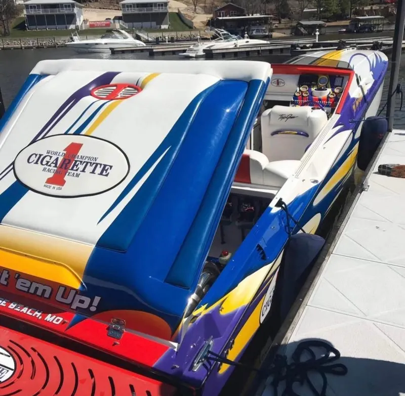 Slide: The Image of 2004 Cigarette 38 Top Gun speedboat with vibrant graphics docked at a marina. - 35