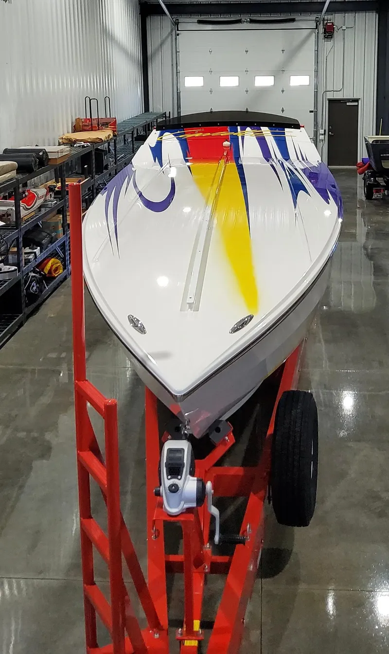 Slide: The Image of 2004 Cigarette 38 Top Gun boat with vibrant graphics on a red trailer in a garage. - 39