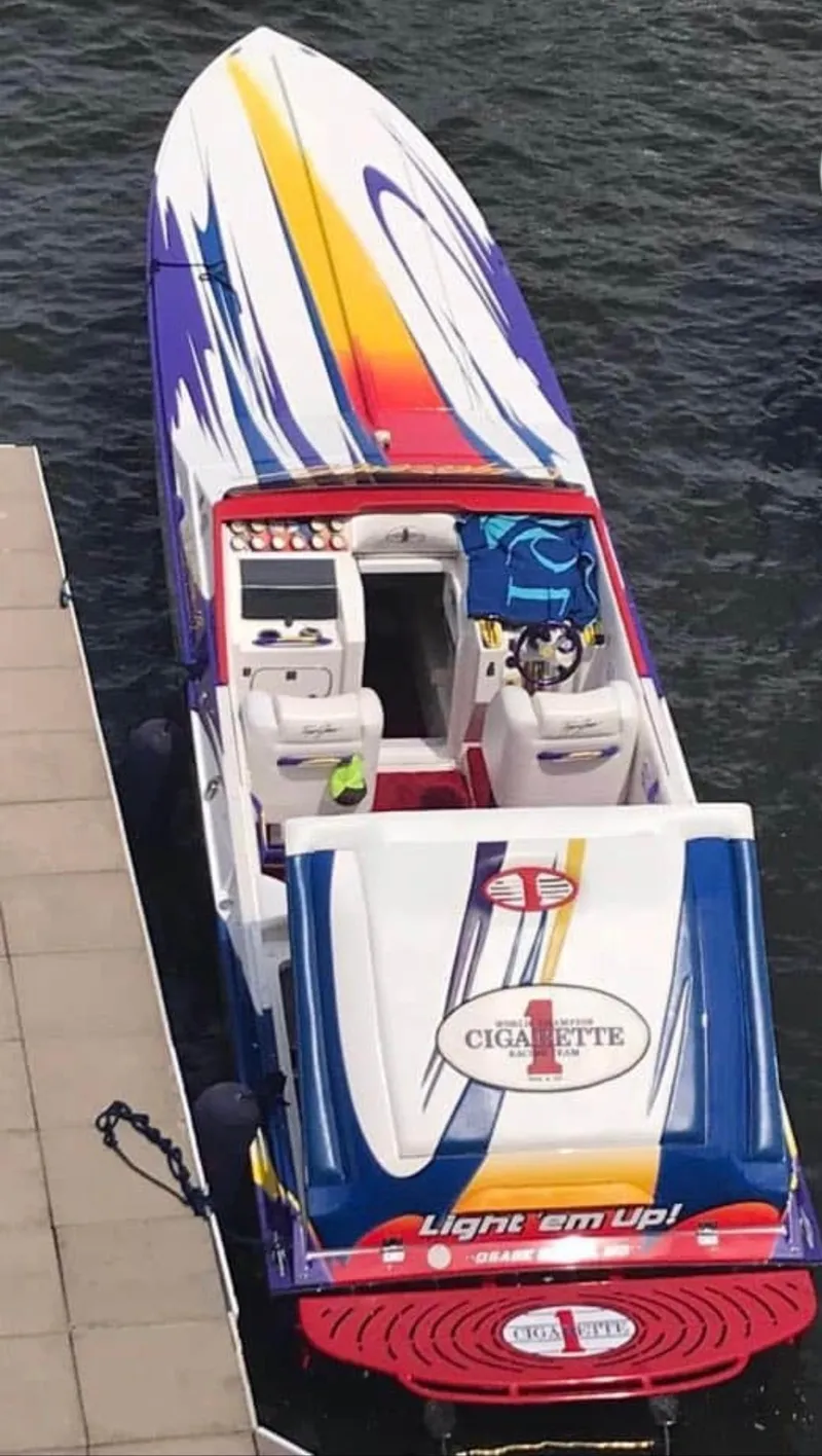 Slide: The Image of 2004 Cigarette 38 Top Gun speedboat with vibrant graphics docked on water. - 45