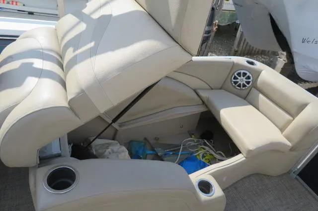 Slide: The Image of 2014 Bennington 2275 GCW boat interior with beige seating and storage compartment open. - 8