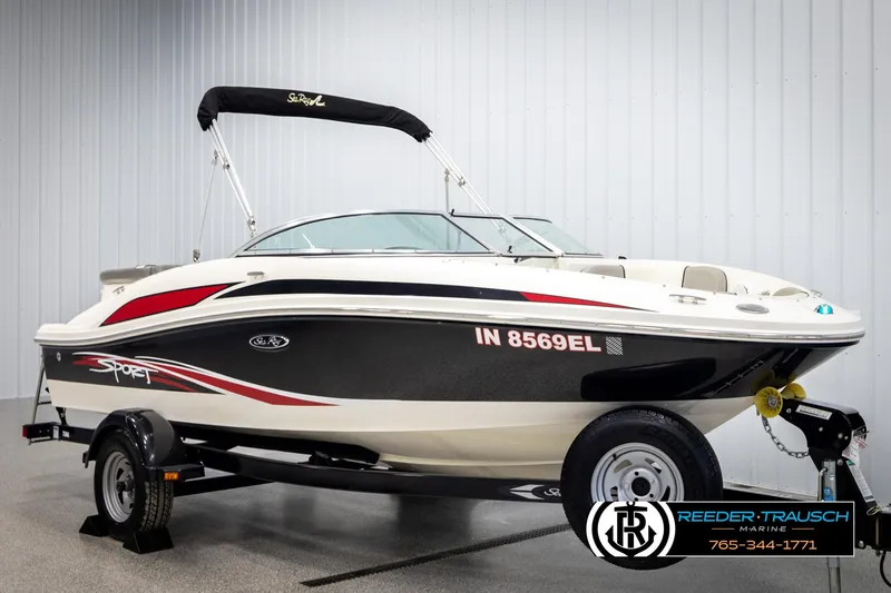 Slide: The Image of 2011 Sea Ray 185 Sport boat with trailer, black and red accents, displayed indoors. - 2