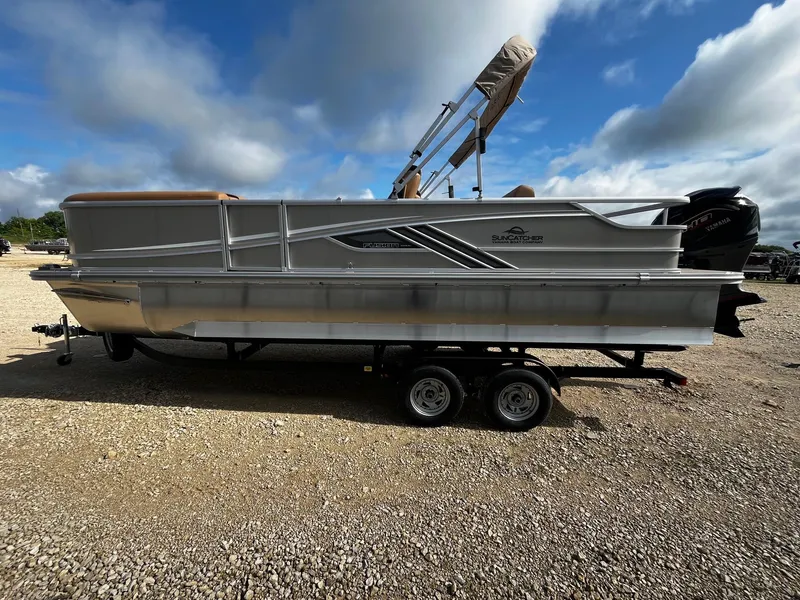 Slide: The Image of 2025 SunCatcher Fusion 324SL pontoon boat on a trailer under a cloudy sky. - 4