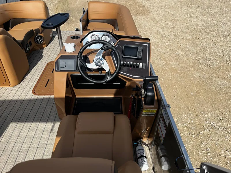 Slide: The Image of 2025 SunCatcher Fusion 324SL boat interior with steering wheel, dashboard, and tan seating. - 9