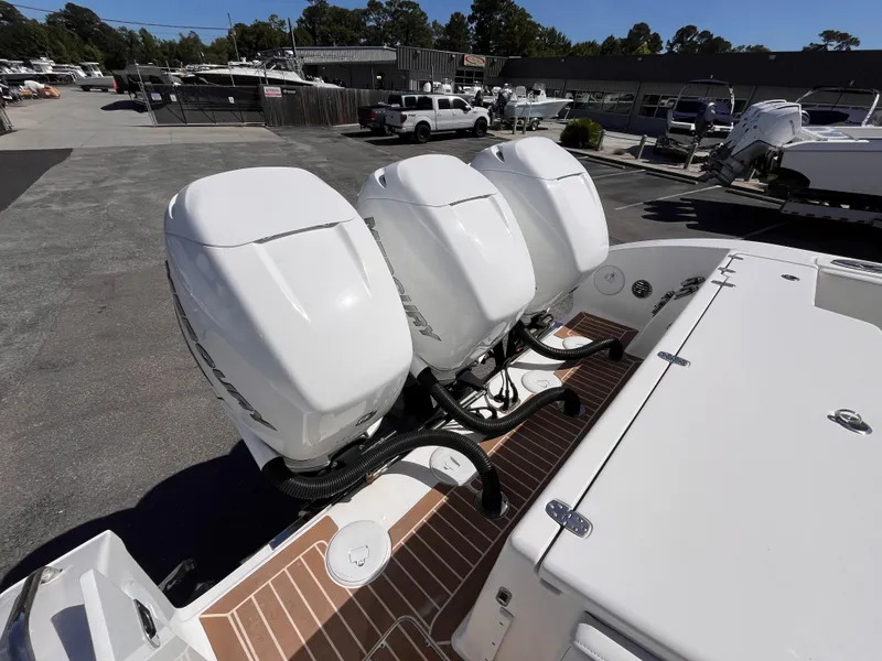 Slide: The Image of Triple outboard engines on a 2021 Fountain 38 SFC boat in a marina setting. - 21