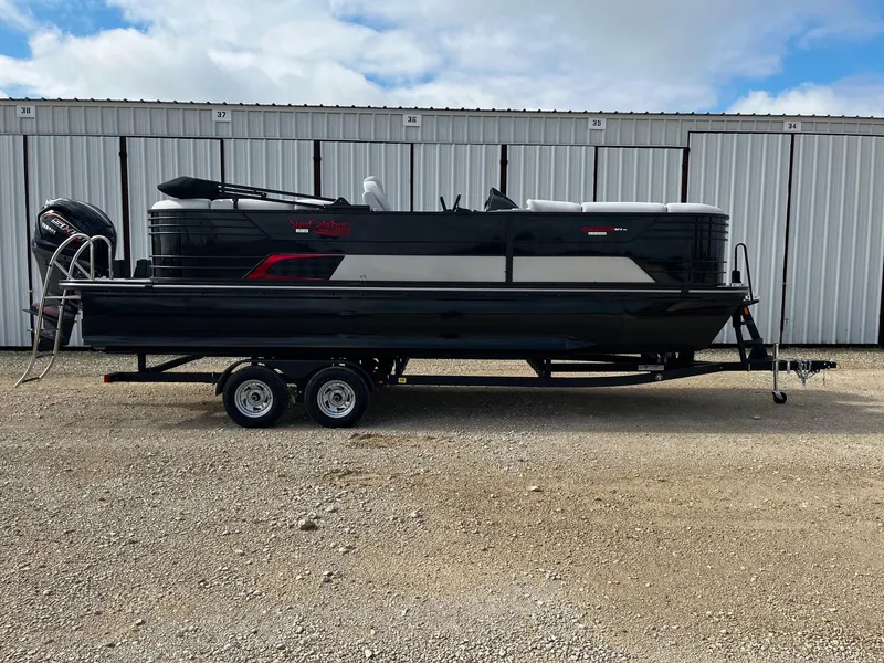 The Image of 2025 SunCatcher Elite 324 RC pontoon boat on trailer, parked outdoors. - 0