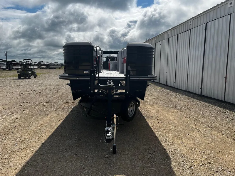 Slide: The Image of 2025 SunCatcher Elite 324 RC pontoon boat on a trailer, parked outdoors. - 2