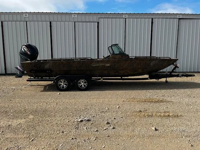 Slide: The Image of 2025 G3 Sportsman 2400 boat on trailer, parked in front of storage units. - 0
