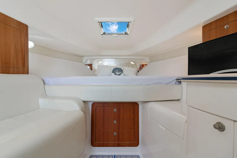 Slide: The Image of Interior of 2004 Intrepid 377 Walkaround boat, featuring cozy cabin with skylight and wood accents. - 29