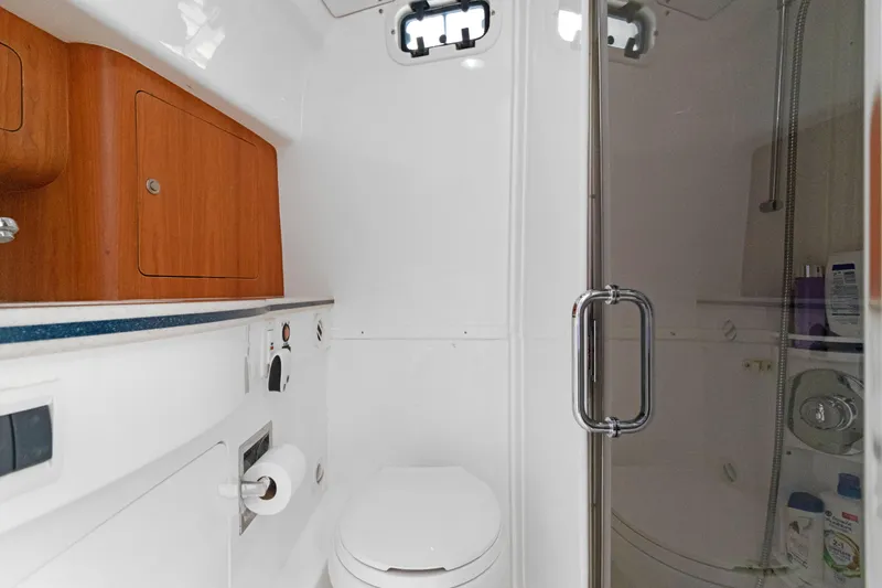 Slide: The Image of 2004 Intrepid 377 Walkaround boat bathroom with shower, wooden cabinet, and white fixtures. - 37