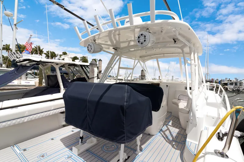 Slide: The Image of 2004 Intrepid 377 Walkaround boat docked, featuring covered seating and modern amenities. - 43