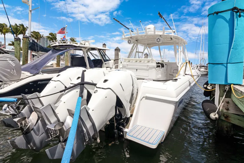 Slide: The Image of 2004 Intrepid 377 Walkaround boat docked with powerful outboard engines, under a clear blue sky. - 49