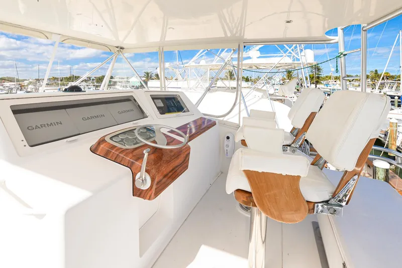 Slide: The Image of 1999 Viking 55 Convertible yacht helm with Garmin displays and white captain chairs. - 14