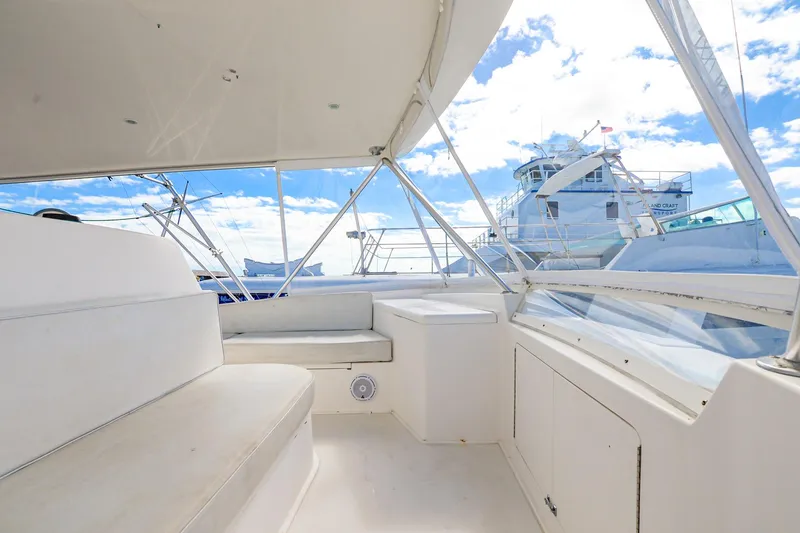 Slide: The Image of 1999 Viking 55 Convertible yacht interior with white seating and clear sky view. - 18
