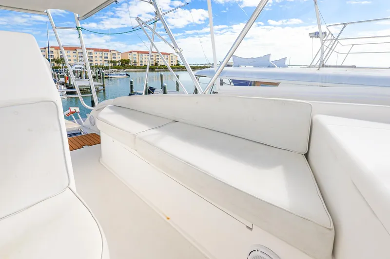 Slide: The Image of 1999 Viking 55 Convertible yacht with white seating, docked at a marina under a clear sky. - 19